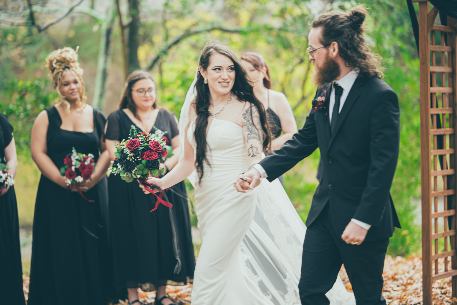 Wedding party celebrating outdoors under natural greenery and trees.