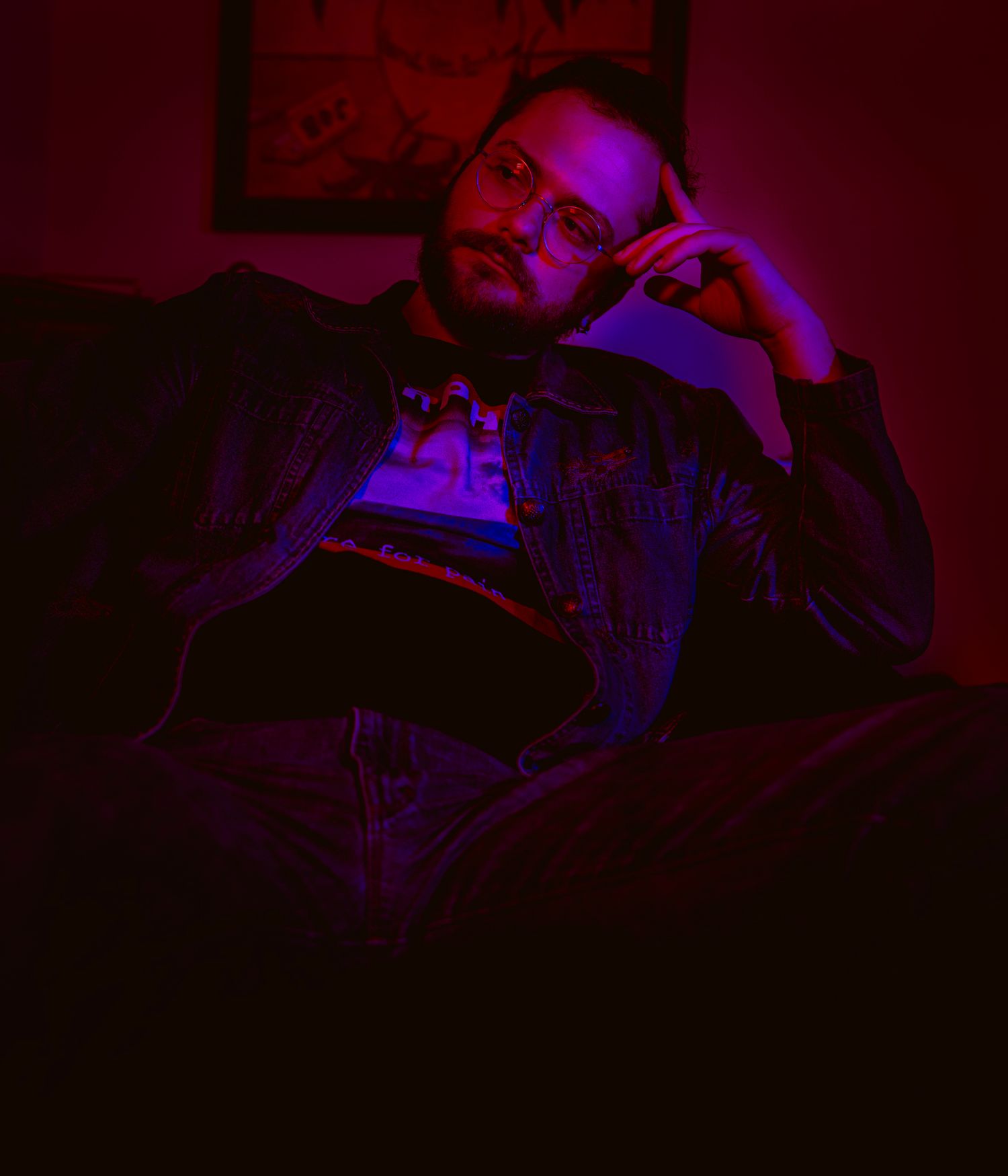 Bass guitar player performing in dramatic red and purple stage lighting.