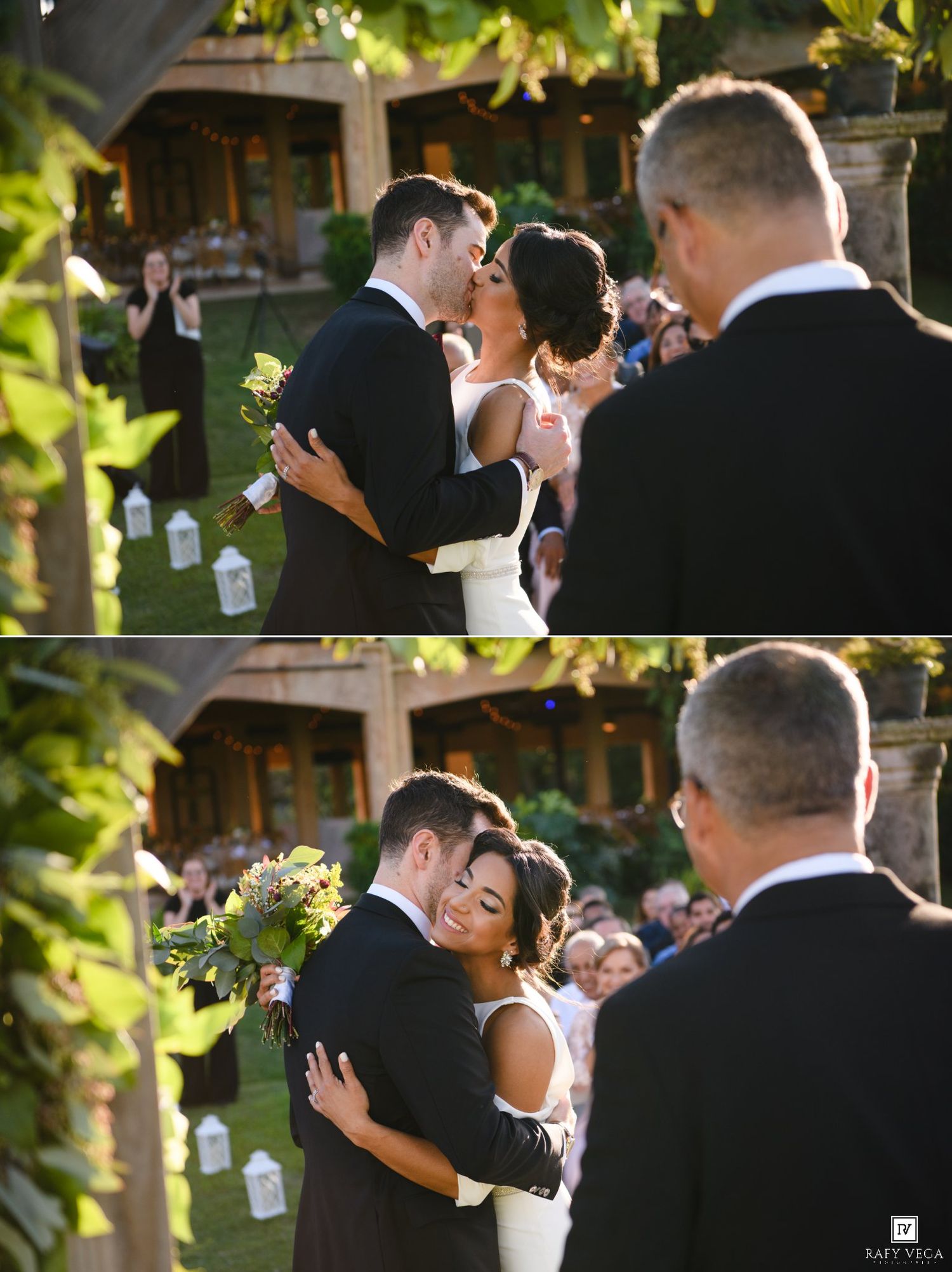 Bride and groom share their first kiss at an outdoor wedding ceremony surrounded by guests.