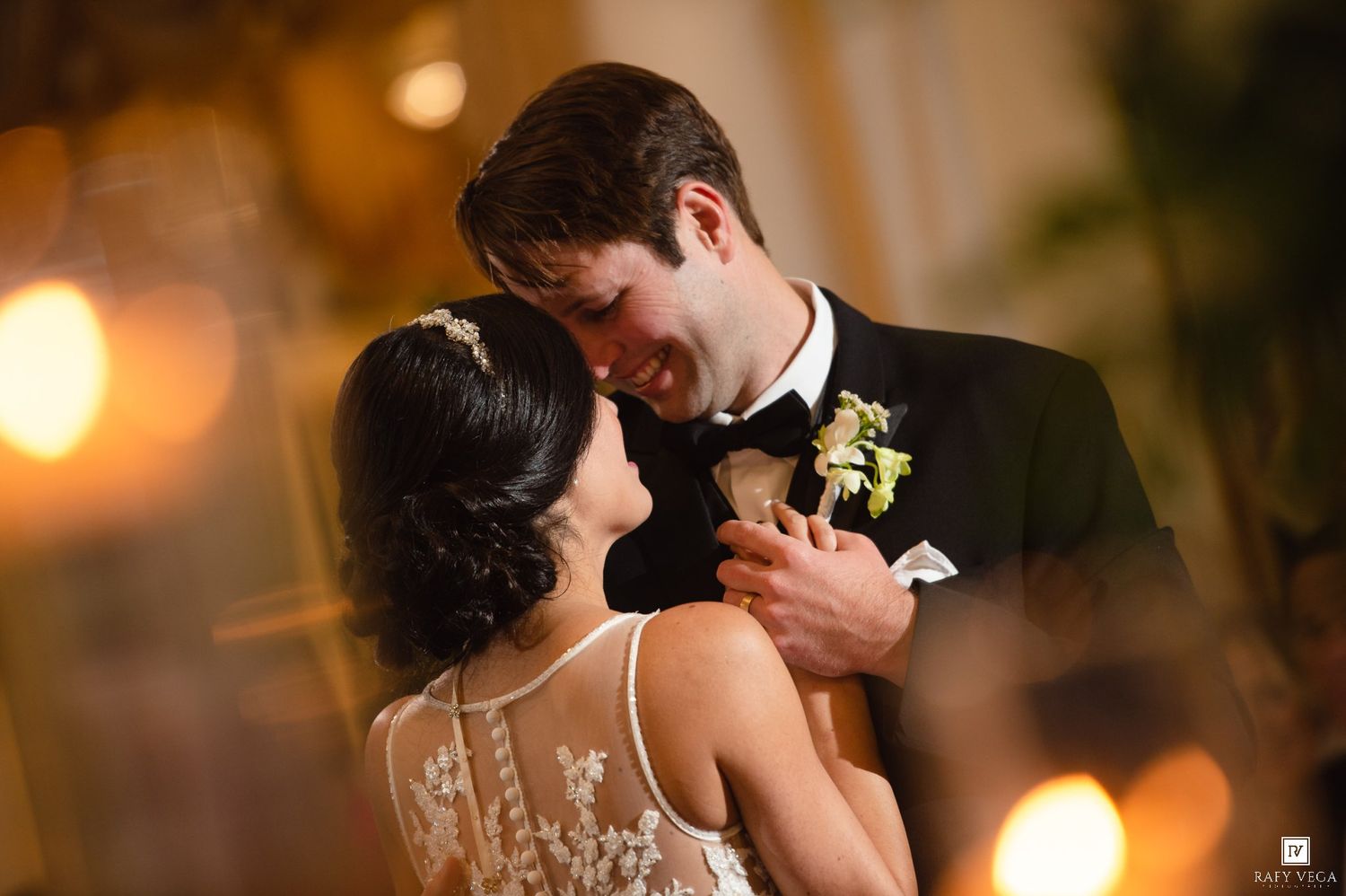 A bride and groom share an intimate moment during their first dance, surrounded by warm candlelight at their wedding reception.