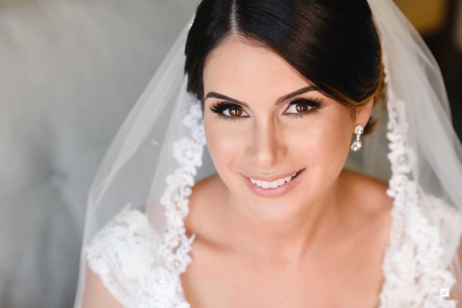 Beautiful bride wearing lace veil and white gown with elegant makeup on her wedding day.