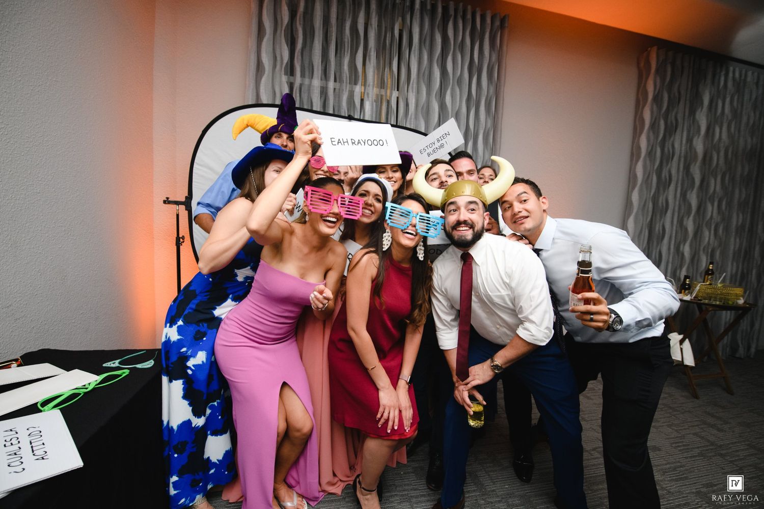Group of friends posing with colorful photo booth props at a festive wedding reception party.