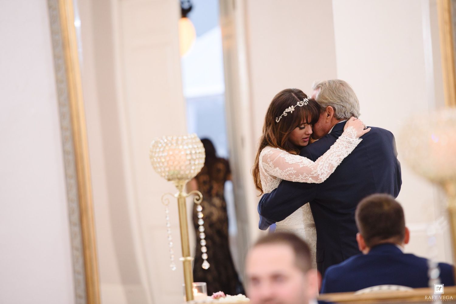 Bride and groom share an emotional embrace during their first dance at an elegant wedding reception venue.