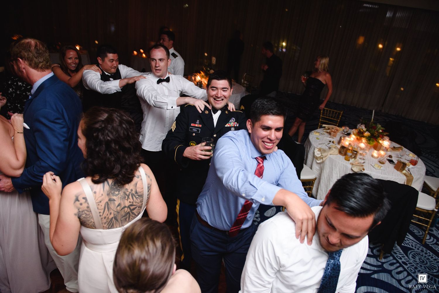 Wedding guests including military personnel dancing and socializing at elegant evening reception.