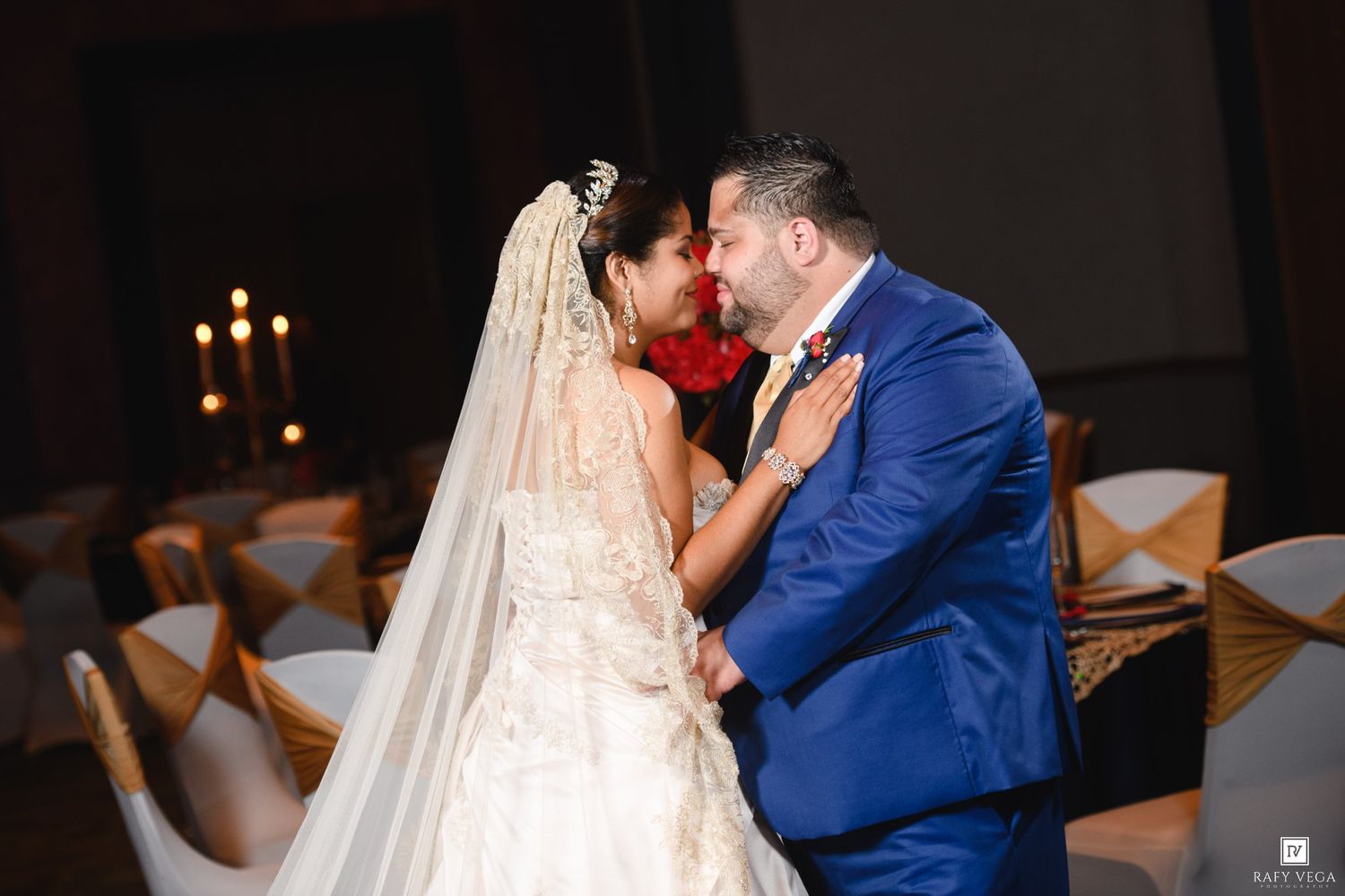 Bride and groom share a romantic first dance kiss at their elegant wedding reception with candlelit decor.