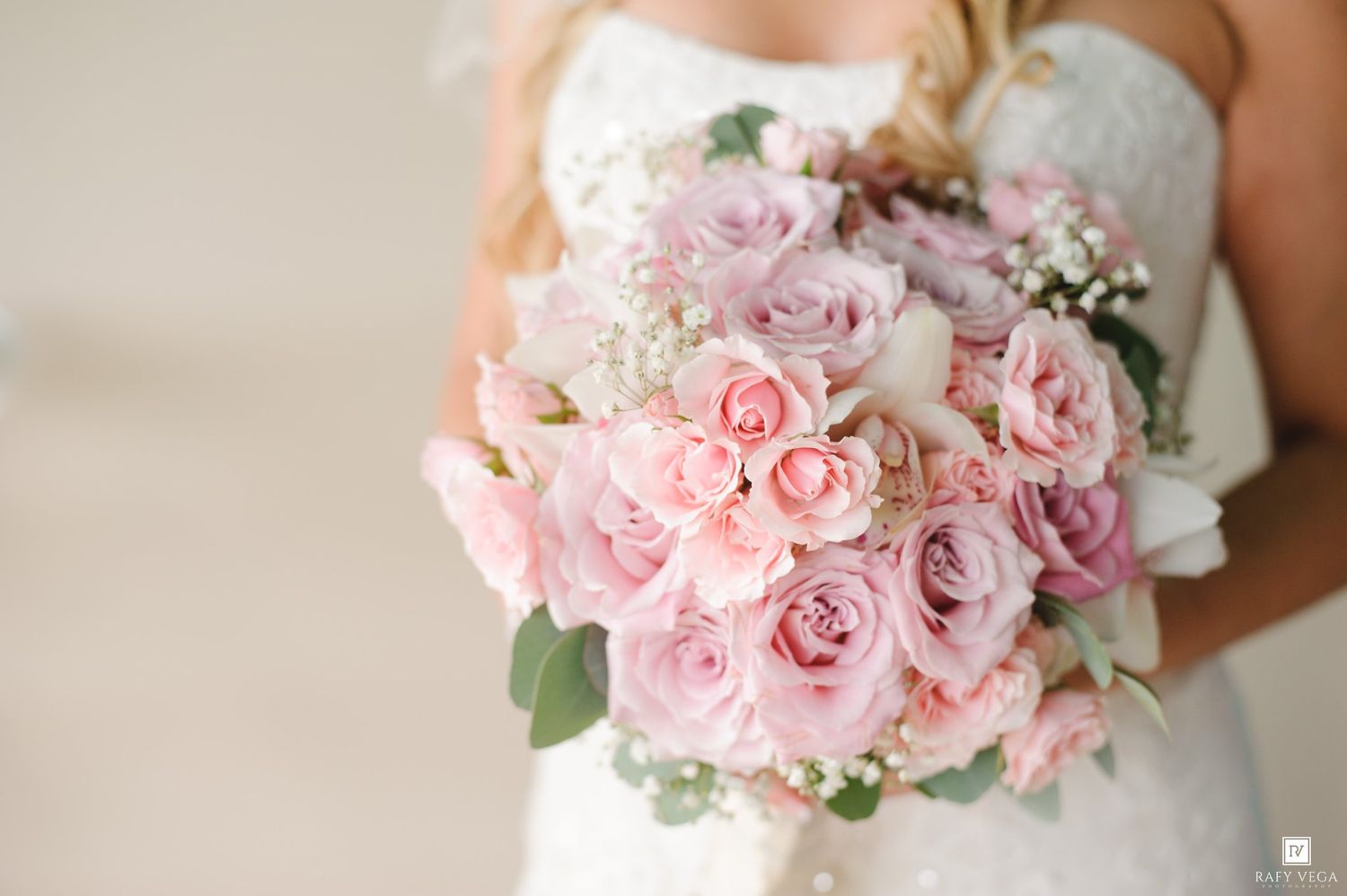 Bride holding a lush pink and lavender rose wedding bouquet with baby's breath accents.