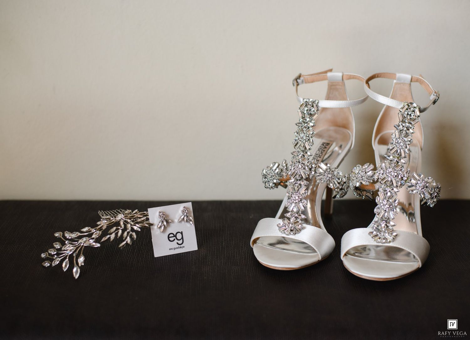 Elegant crystal-embellished bridal heels displayed with silver hair accessories and earrings on a dark surface.