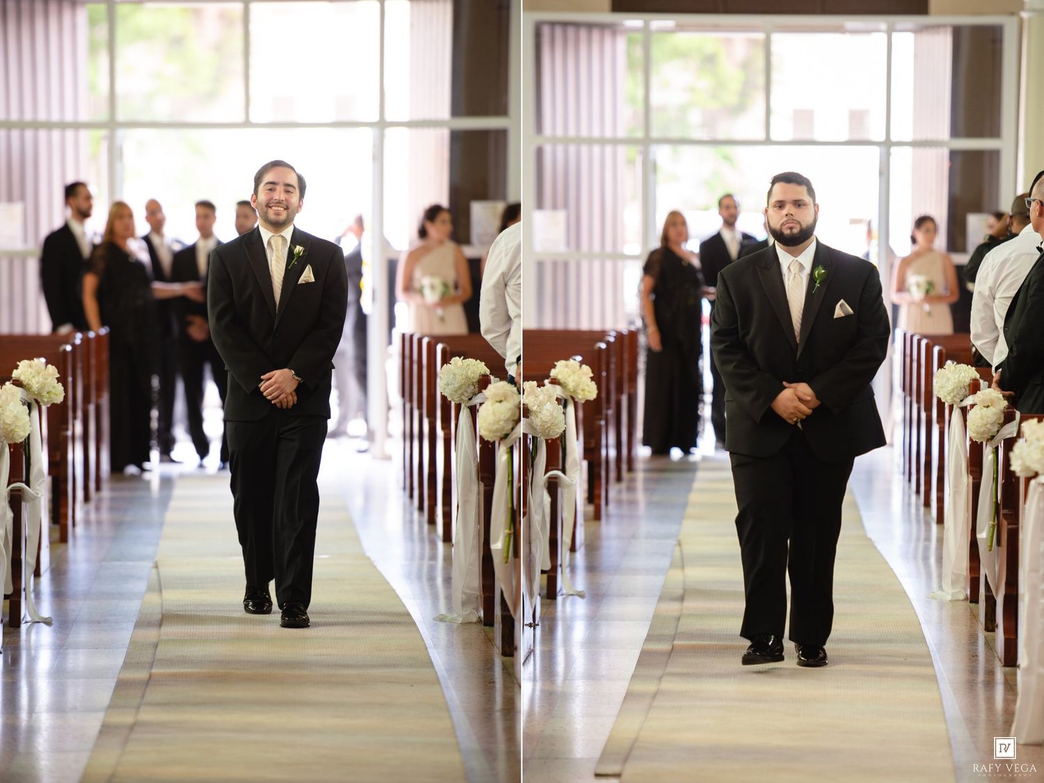 Groomsmen in black tuxedos walk down the aisle of an elegant wedding ceremony venue lined with floral pew markers.