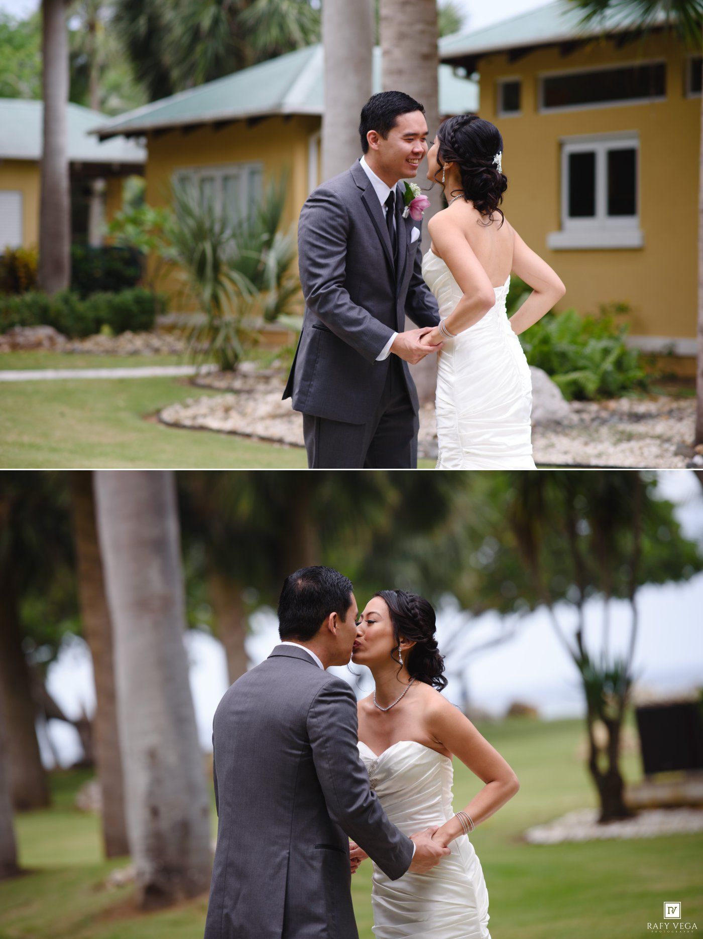 Bride and groom share a tender first look and kiss outdoors near a yellow building and palm trees on their wedding day.