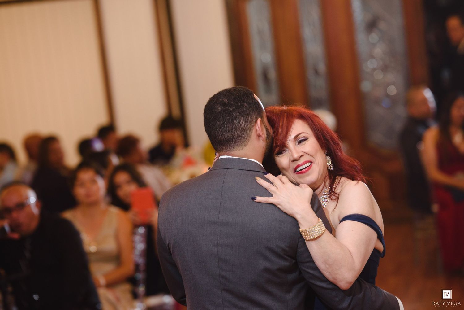 Couple sharing a joyful dance at a wedding reception, woman with red hair smiling warmly in elegant attire.