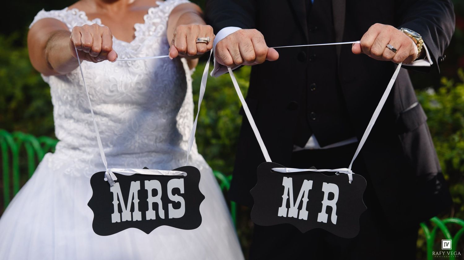 Bride and groom holding MRS and MR wedding signs at outdoor ceremony.
