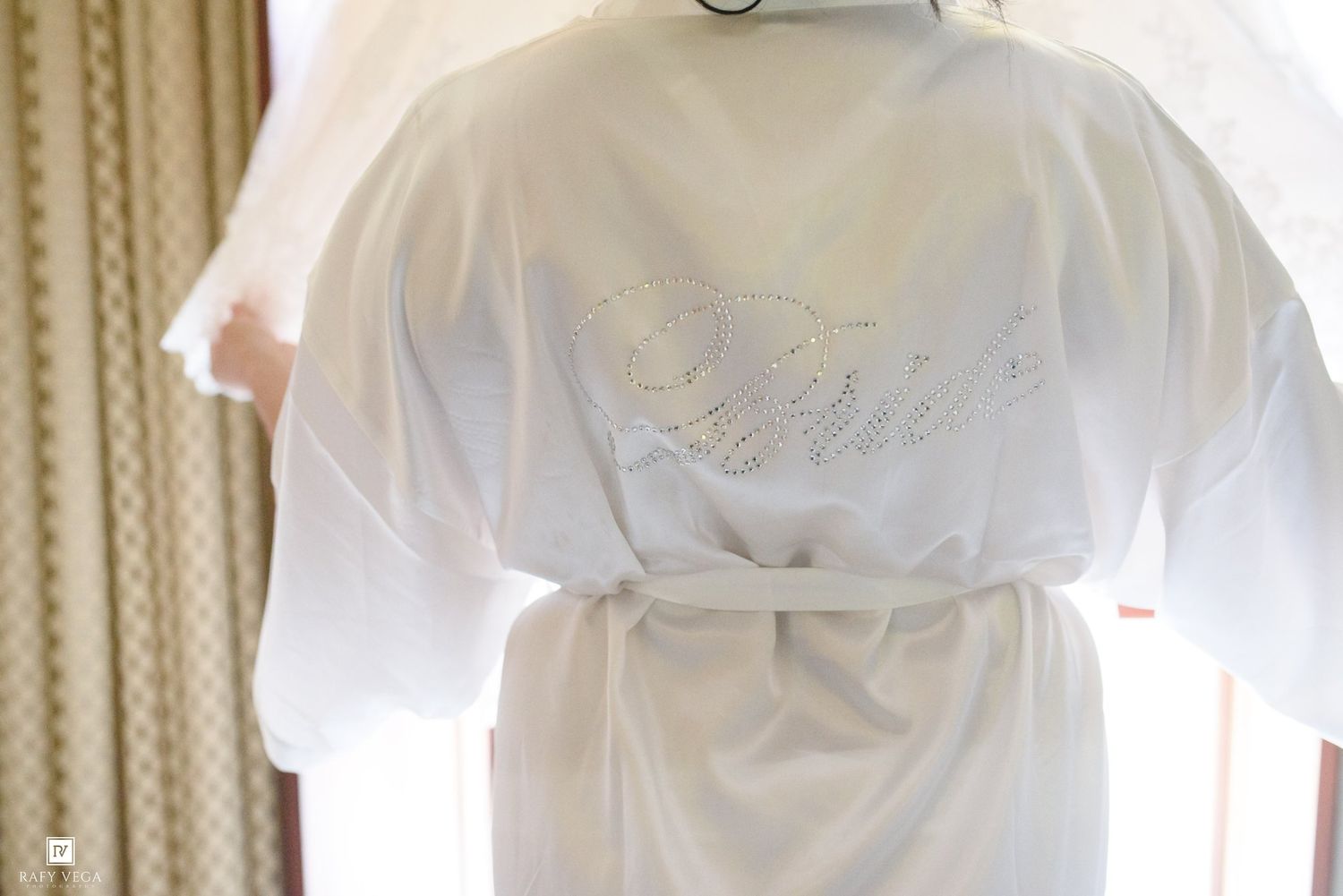 White satin bridal robe with embroidered Bride text hanging elegantly, perfect wedding getting ready attire.