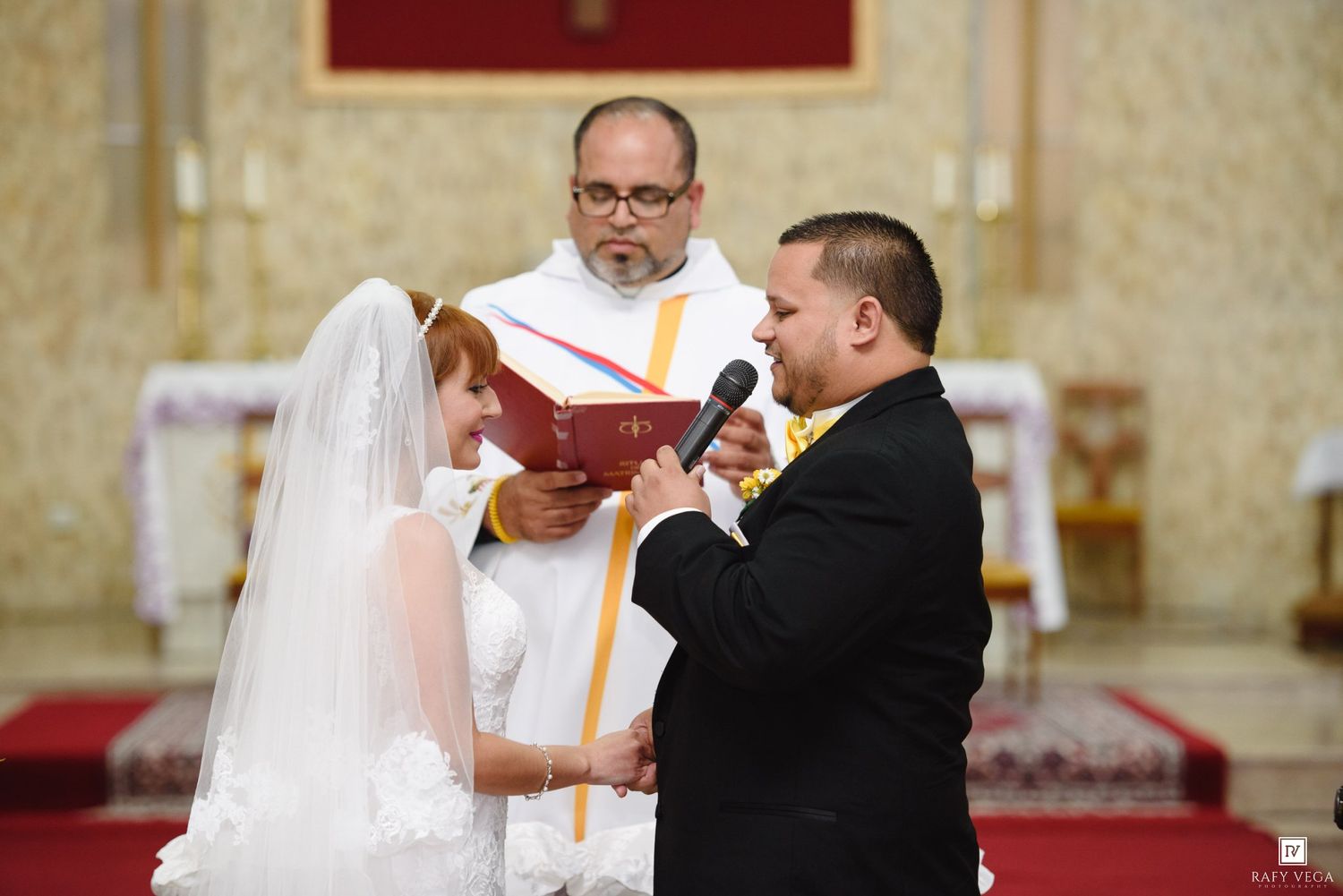 Groom reads wedding vows to bride at church altar ceremony with officiant holding red book.