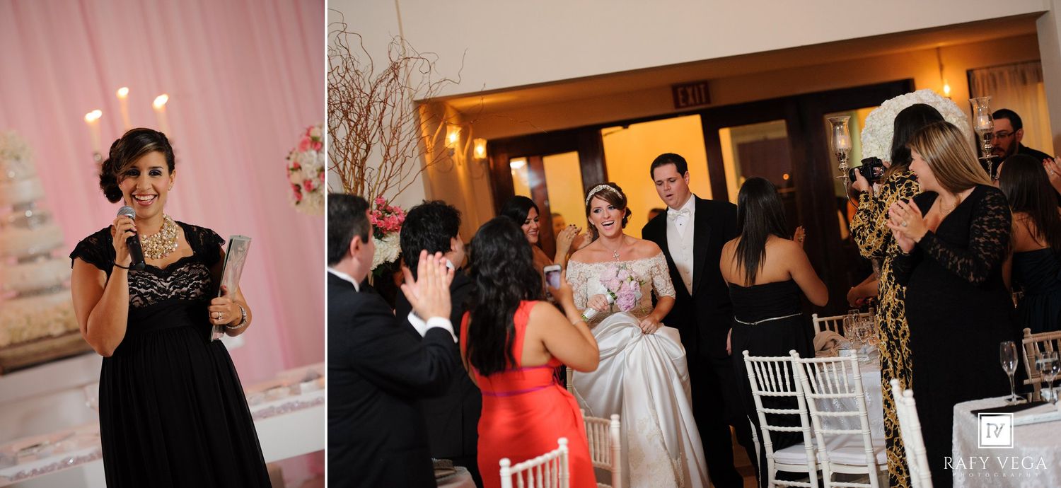 Guests toast and celebrate at an elegant wedding reception with white floral centerpieces and soft pink lighting.