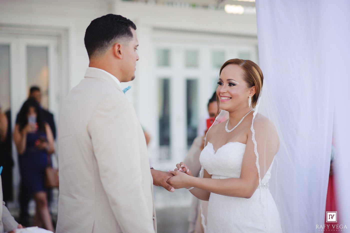 Bride and groom exchange rings during romantic outdoor wedding ceremony, smiling joyfully.
