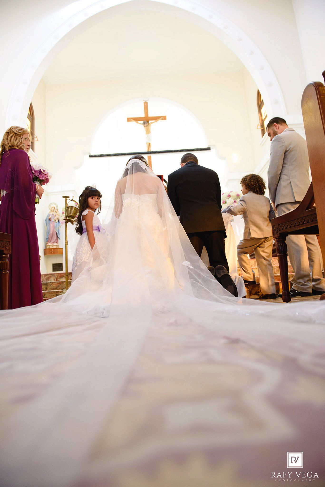 Bride walking down the aisle with flower girl in a Catholic church wedding ceremony.