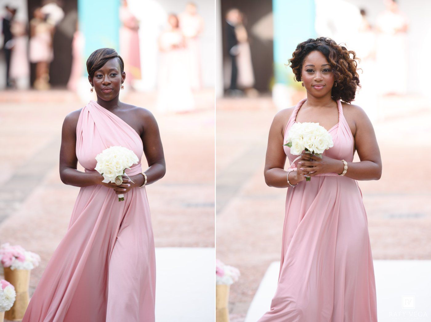Two bridesmaids in blush pink dresses holding white bouquets walking down the wedding aisle.