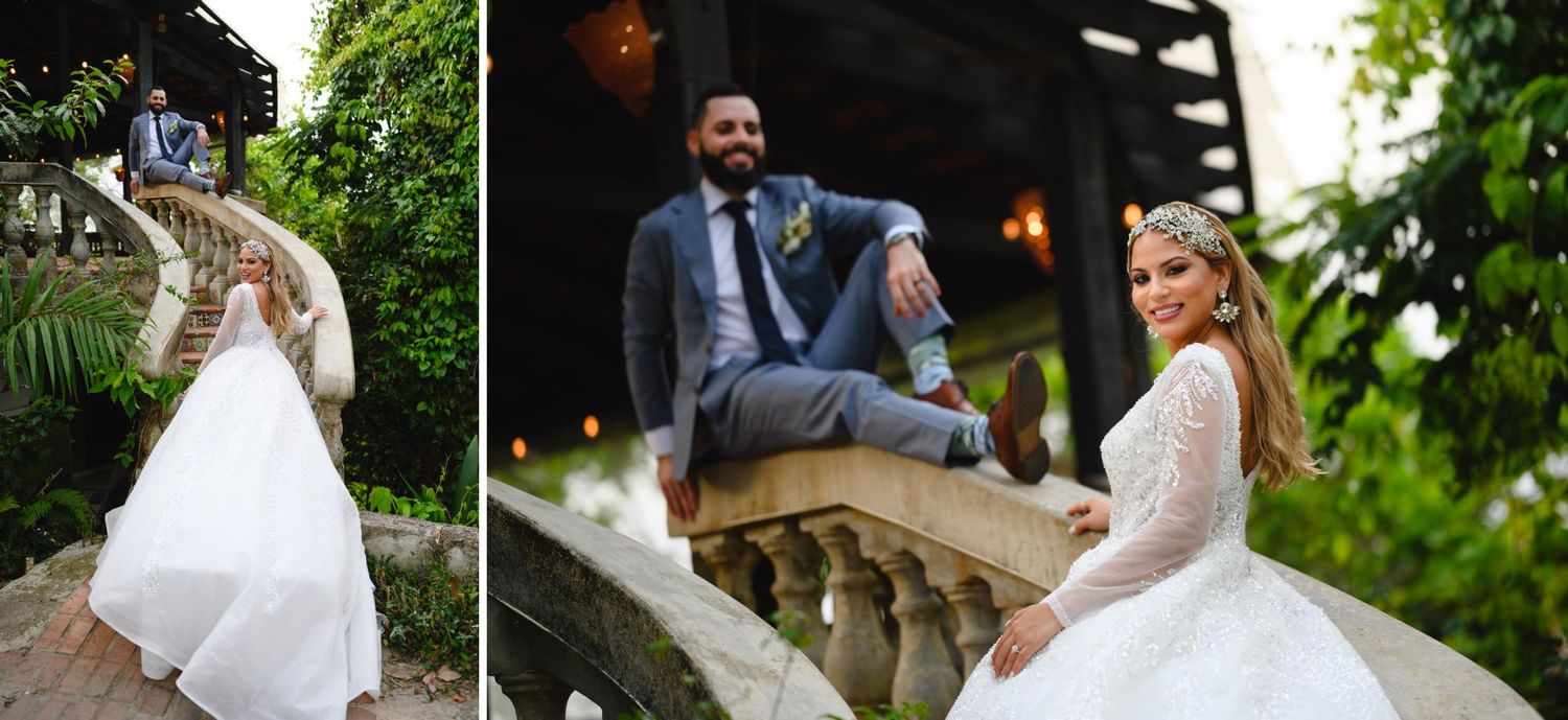 Bride and groom posing elegantly on stone balustrade steps surrounded by lush greenery at outdoor wedding venue.