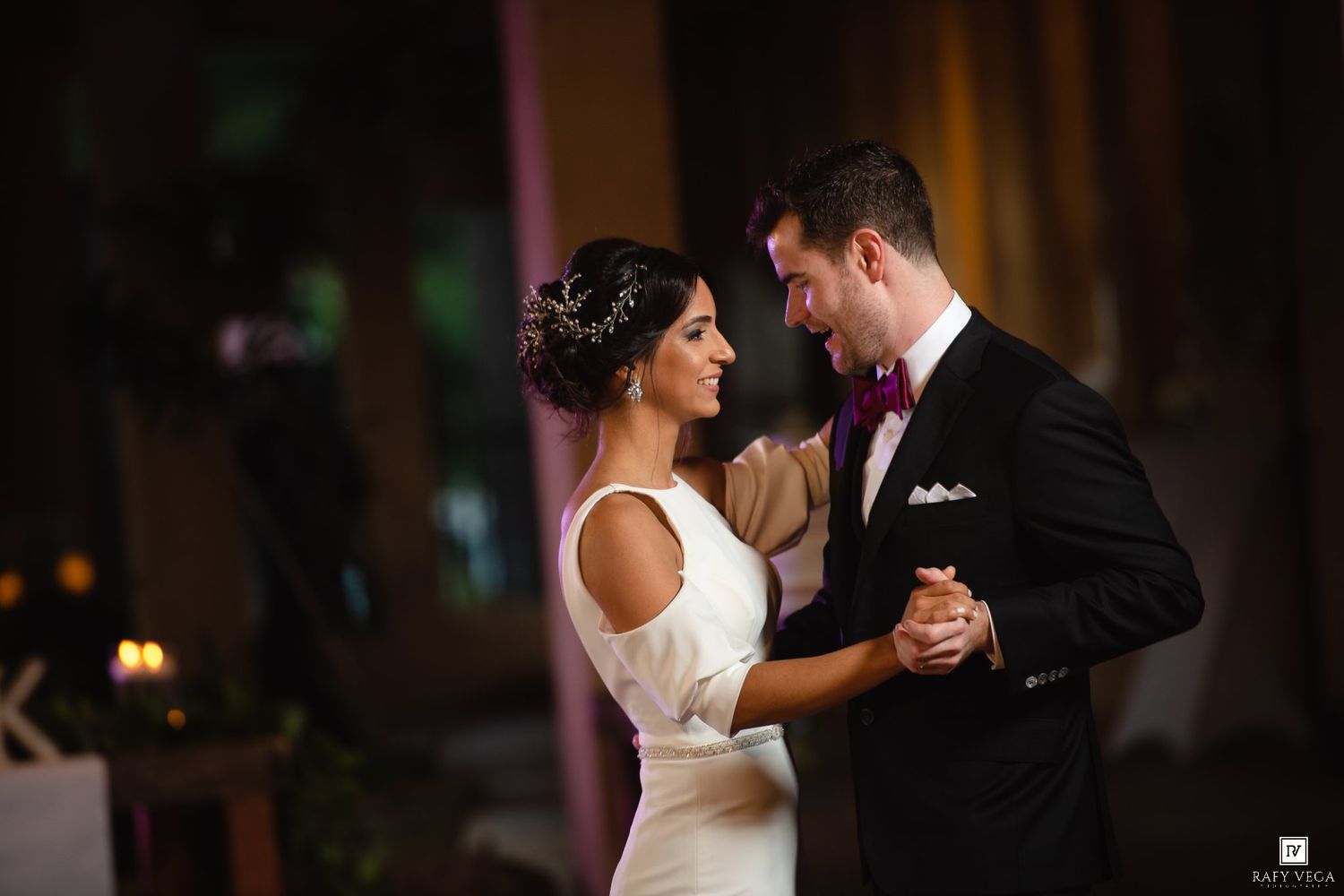 Bride and groom share their first dance, gazing lovingly at each other in elegant wedding attire.