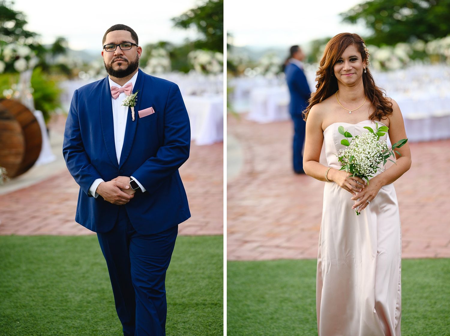 Groom in navy suit with pink bow tie stands beside bridesmaid in white gown holding bouquet at outdoor wedding.