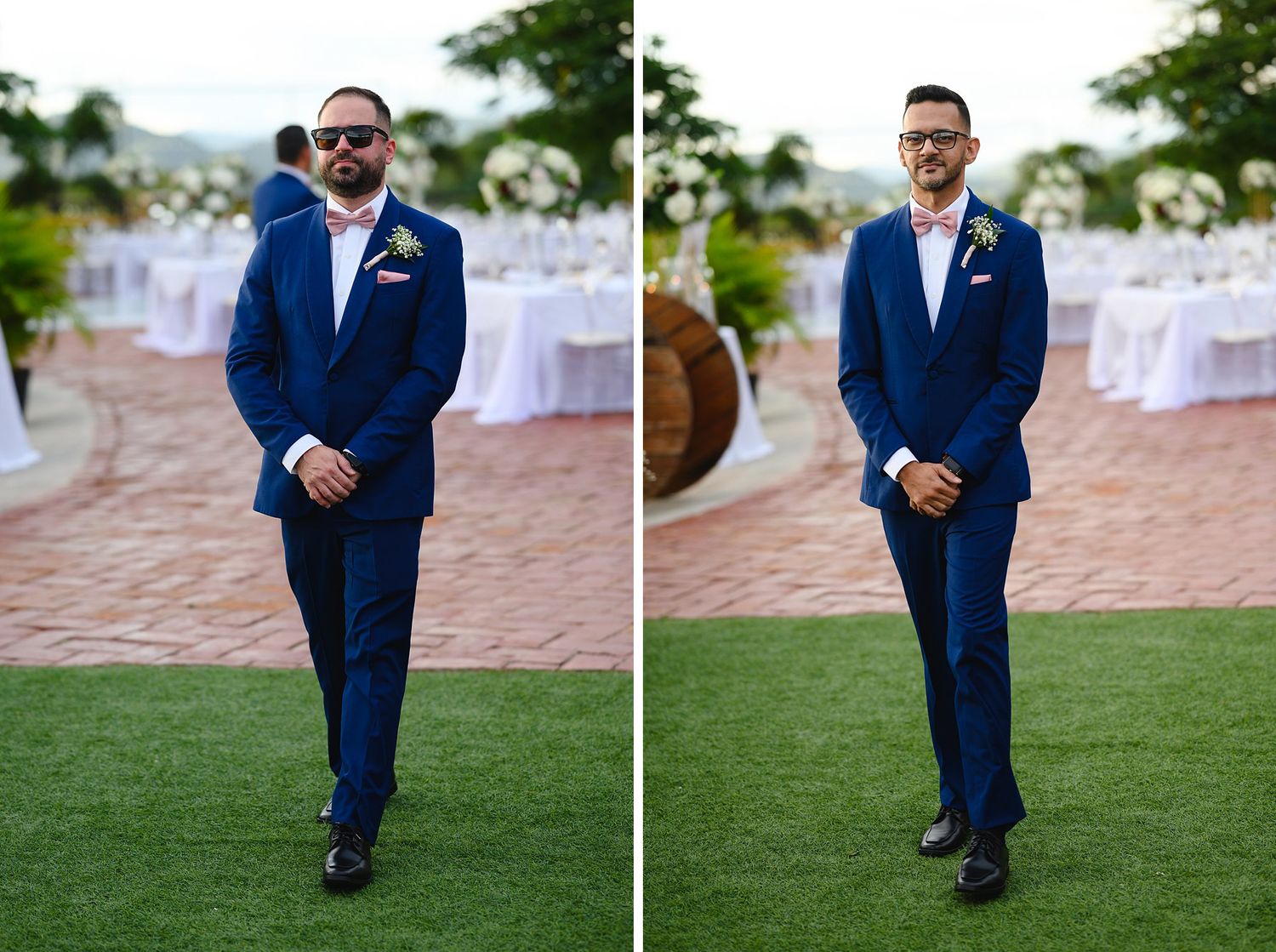 Groom in navy blue suit with boutonniere standing on green lawn at outdoor wedding venue with white floral decorations.