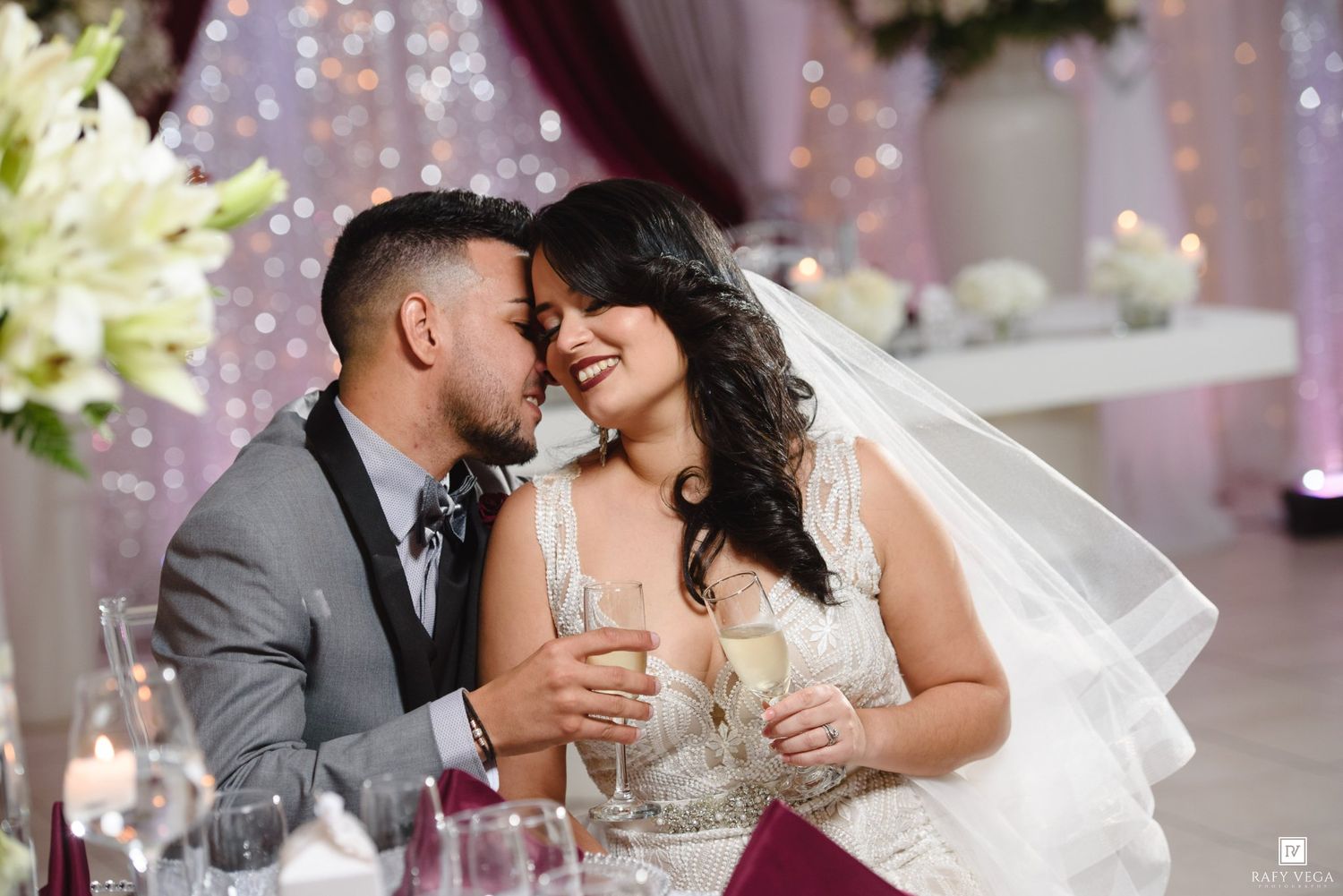 Bride and groom share a romantic moment, clinking champagne glasses at their elegant wedding reception.