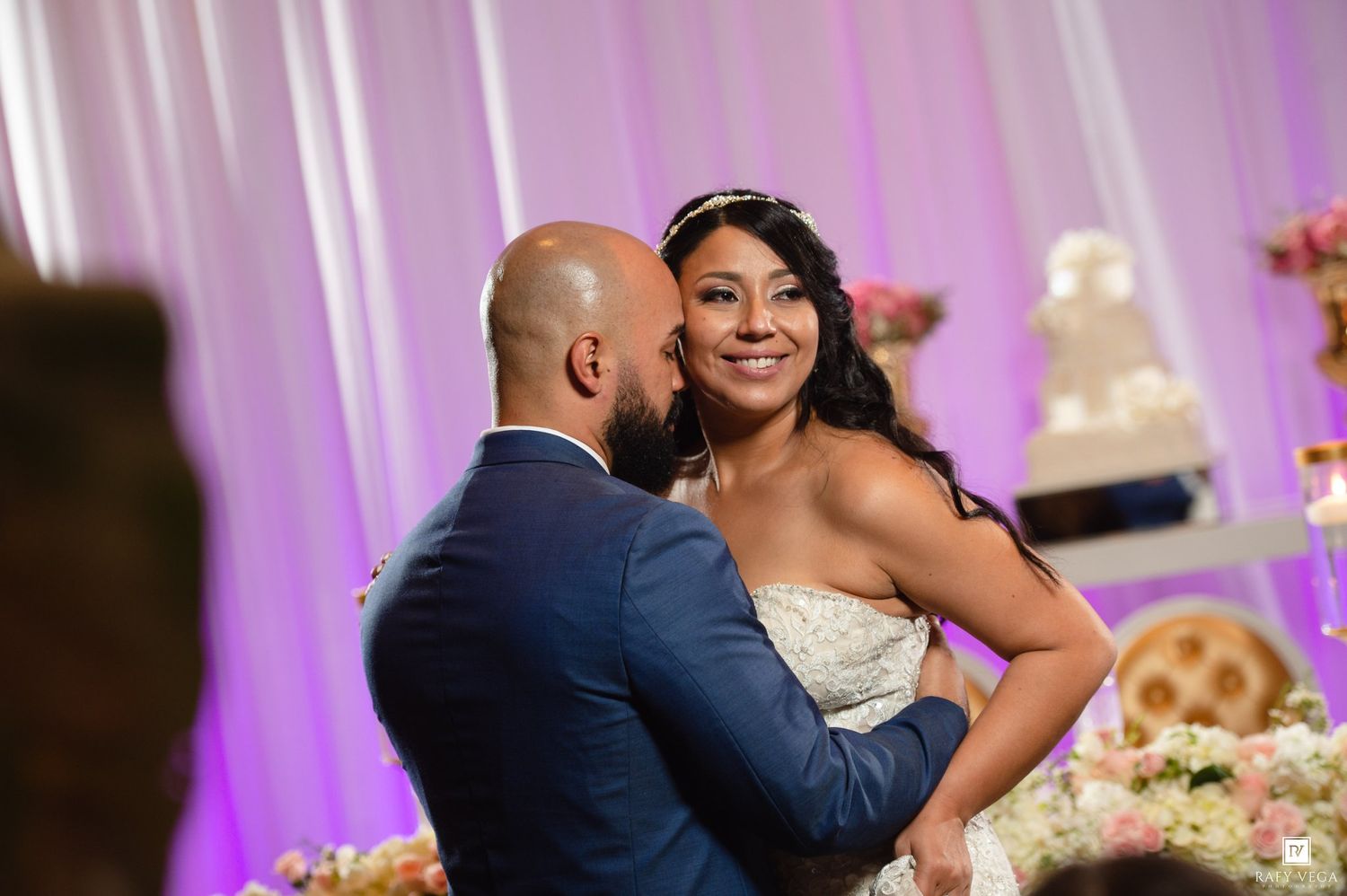 Bride and groom share a tender first dance moment at their elegant wedding reception with floral decor.