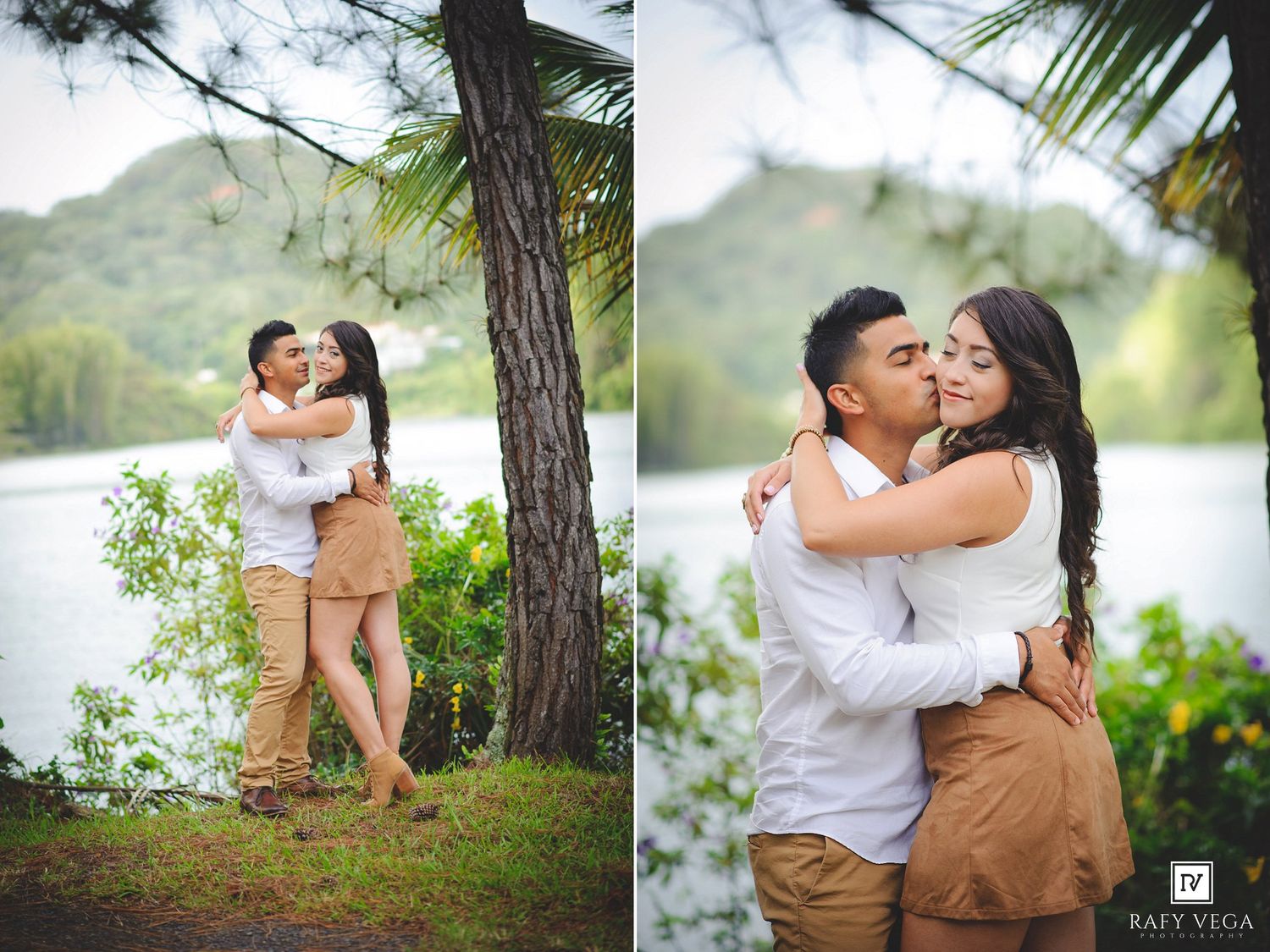 Couple embracing and kissing near a lake surrounded by lush green trees and mountains in a romantic outdoor engagement photo.