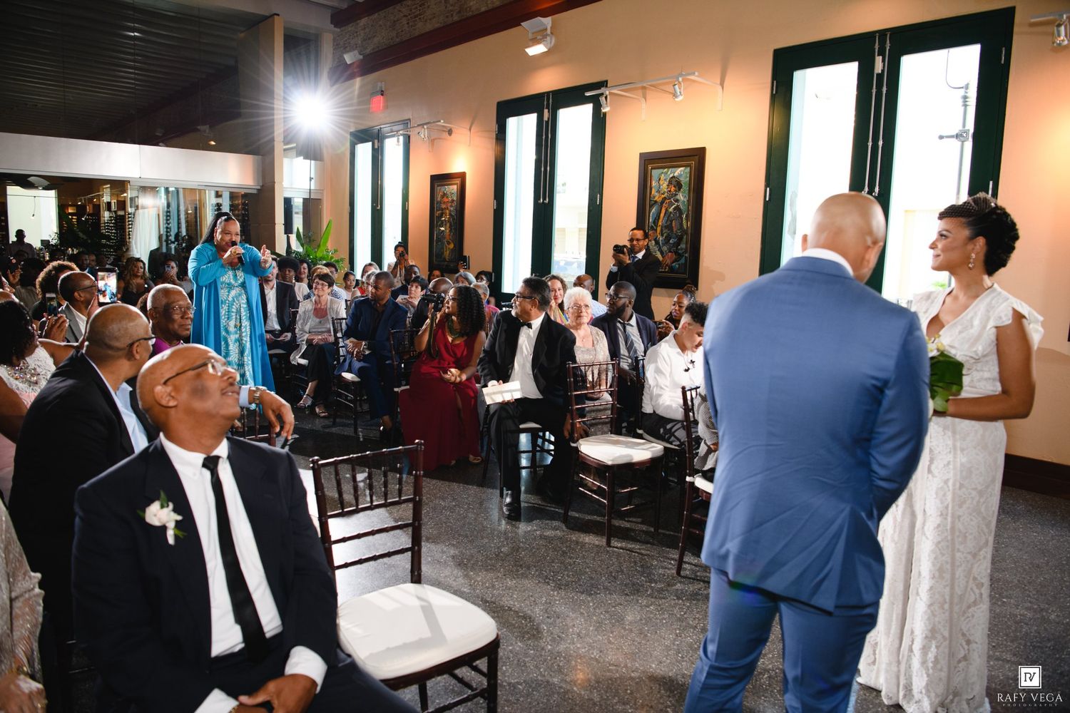 Elegant indoor wedding ceremony with guests seated as bride and groom stand at the altar in a decorated venue.