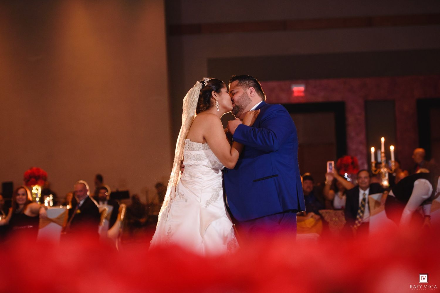 Bride and groom share a romantic first kiss on the dance floor at their elegant wedding reception.