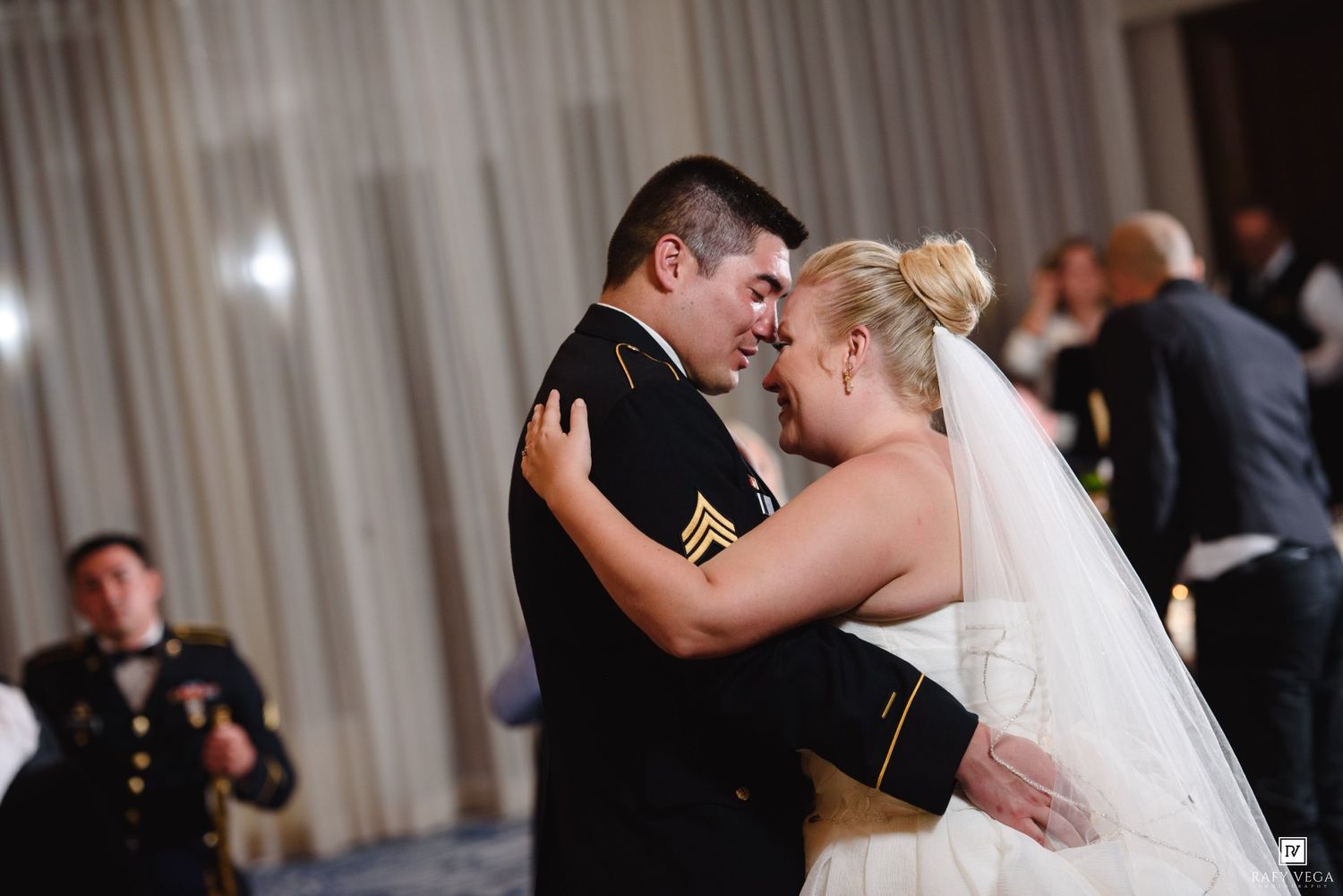 Military groom in uniform shares first dance with bride at wedding reception.