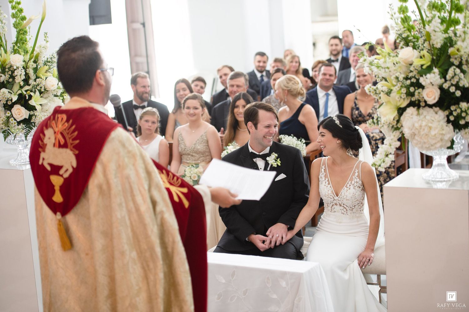 Bride and groom share a joyful moment during their elegant church wedding ceremony with floral arrangements and guests.