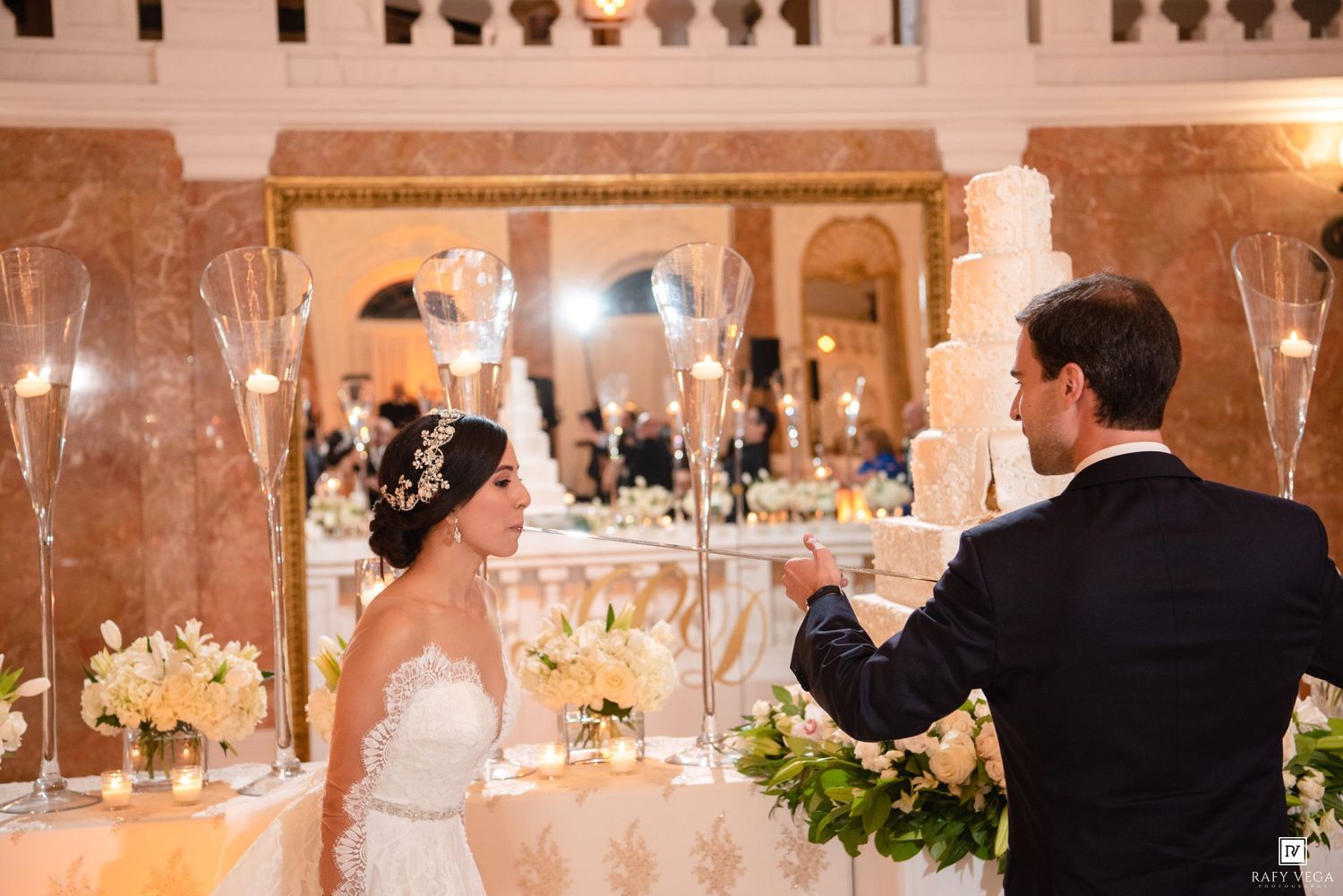 Bride and groom share a toast at an elegant wedding reception with tall candle arrangements and white floral centerpieces.