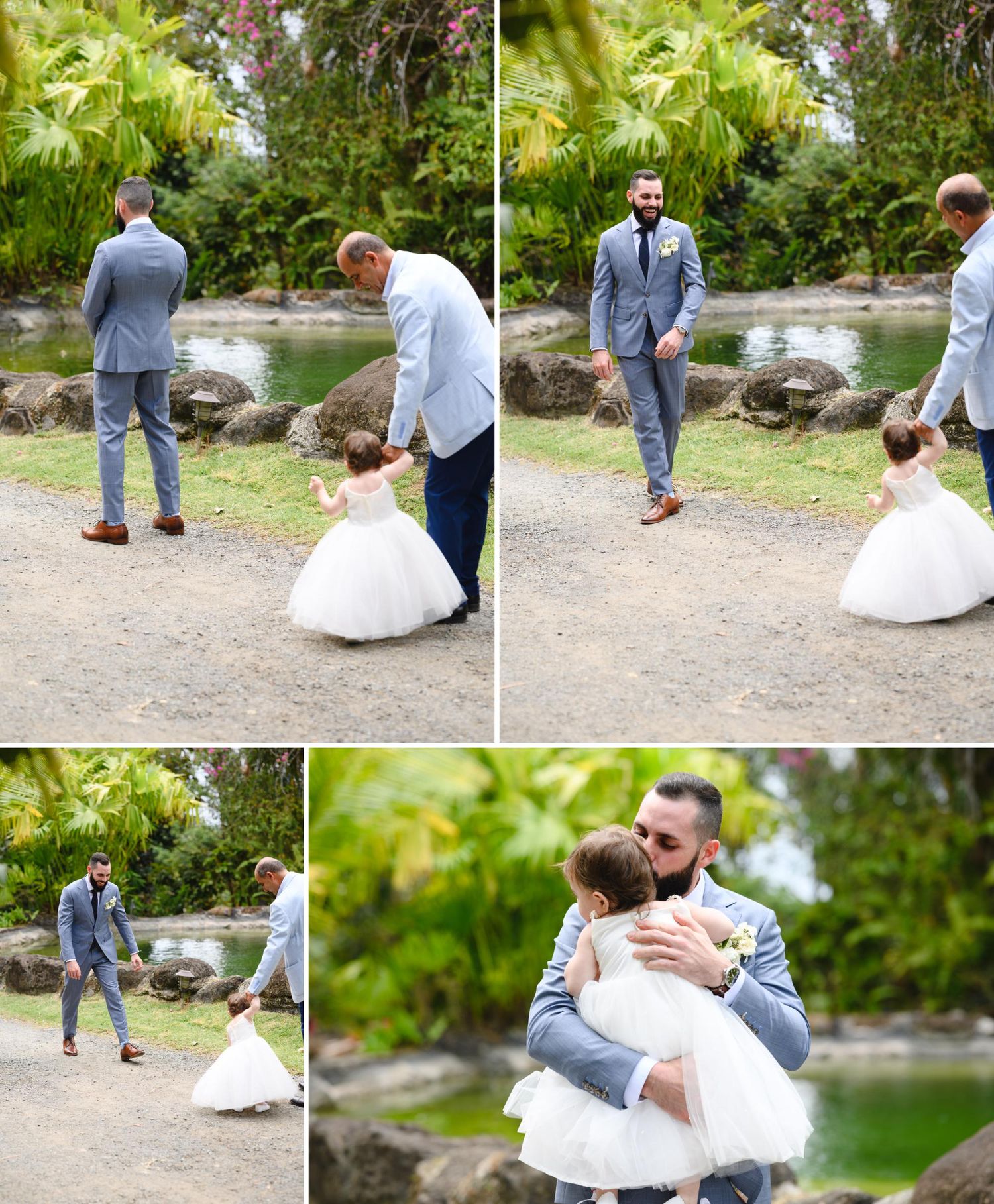 Groom in gray suit shares tender first look moment with flower girl in white dress at tropical outdoor wedding venue.