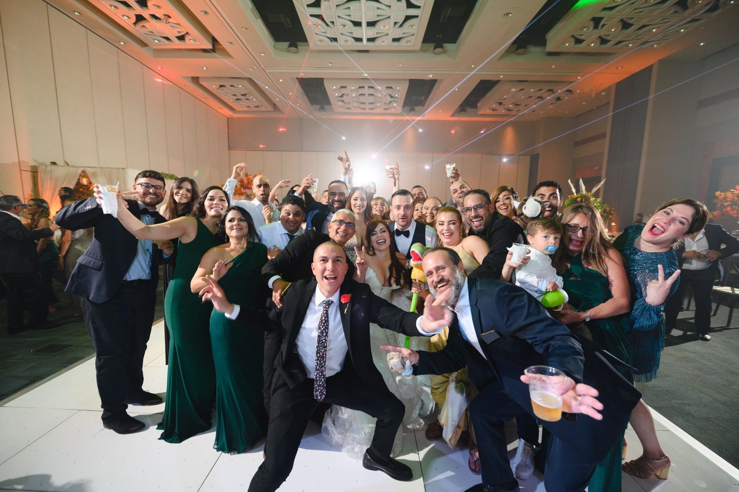 Large group of wedding guests posing and celebrating together on the dance floor at the reception.