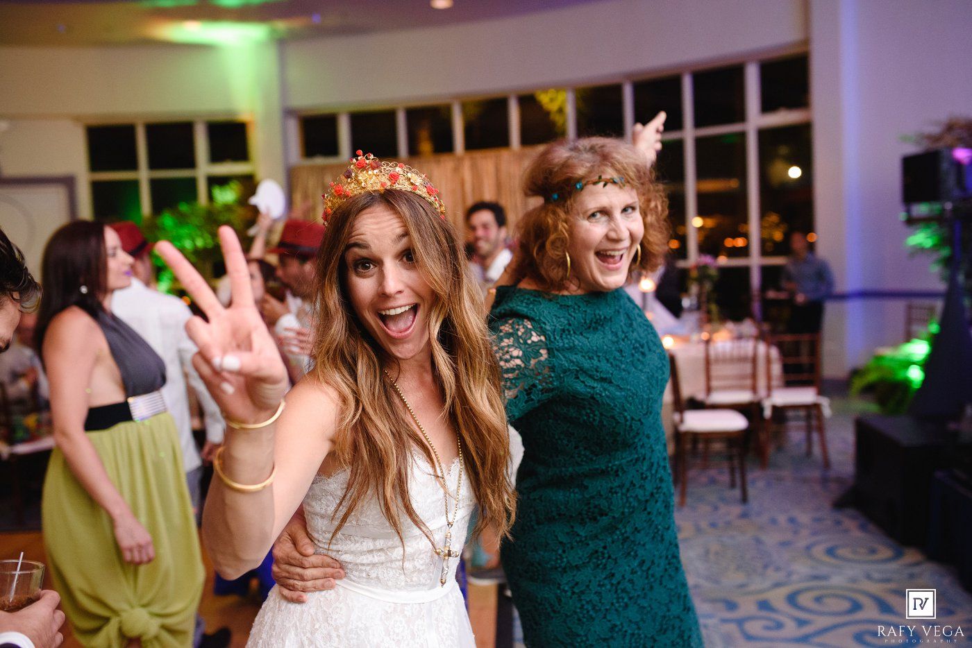 Bride and guest posing playfully with peace signs at a wedding reception.
