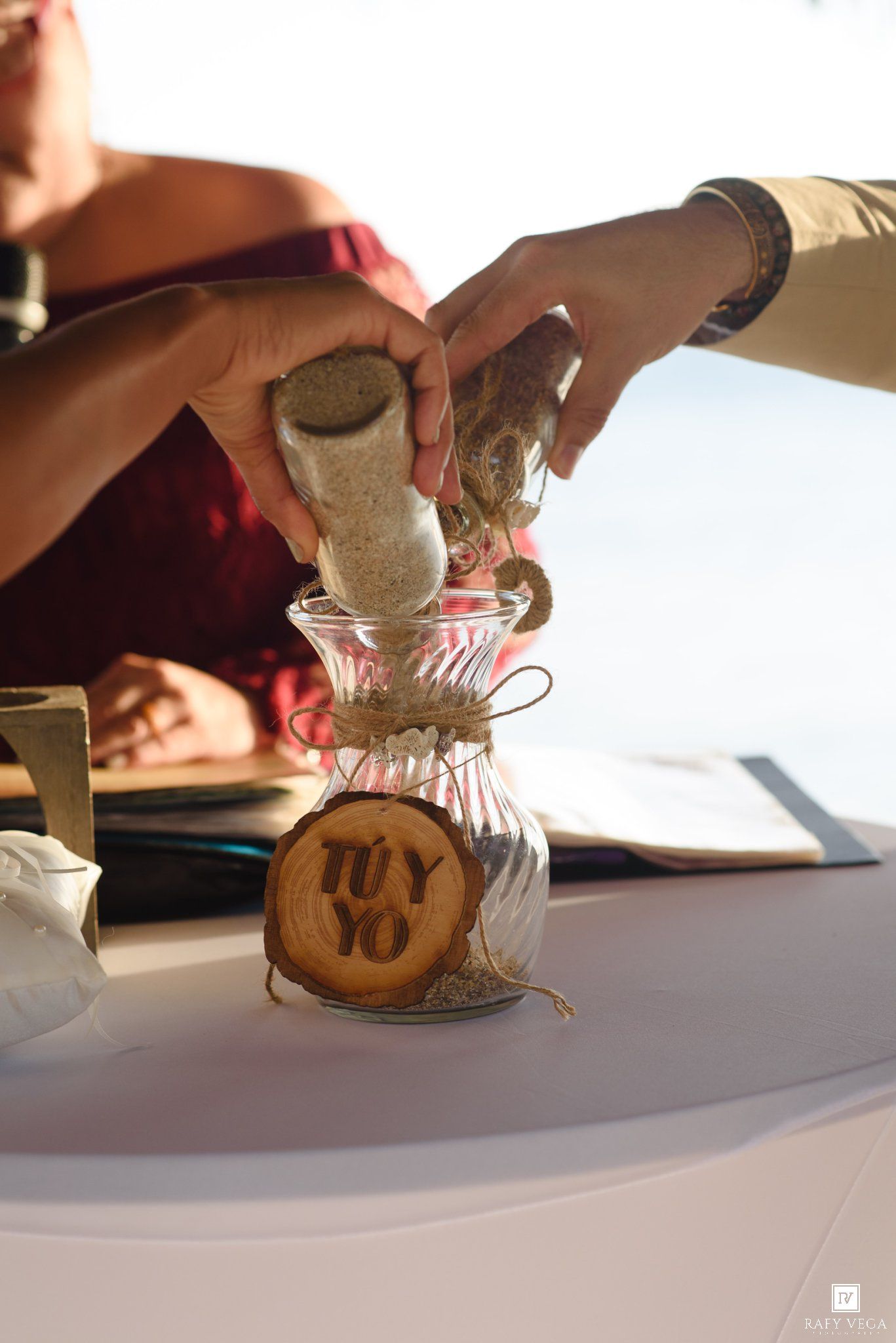 Couple pouring sand into a jar labeled 'Tu y Yo' during a wedding unity ceremony.