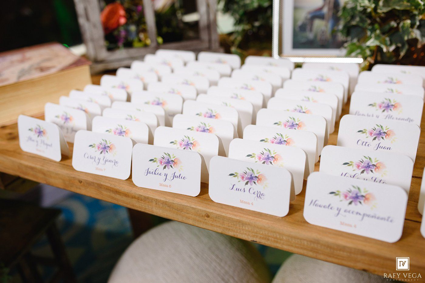 Elegant floral escort cards displayed on a wooden table at a wedding reception venue.