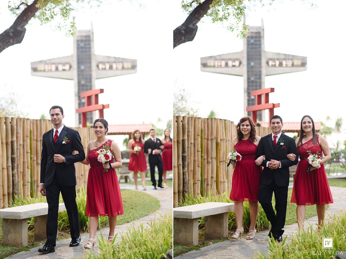 Wedding party in red dresses and black suits pose outdoors near bamboo fence and decorative cross.
