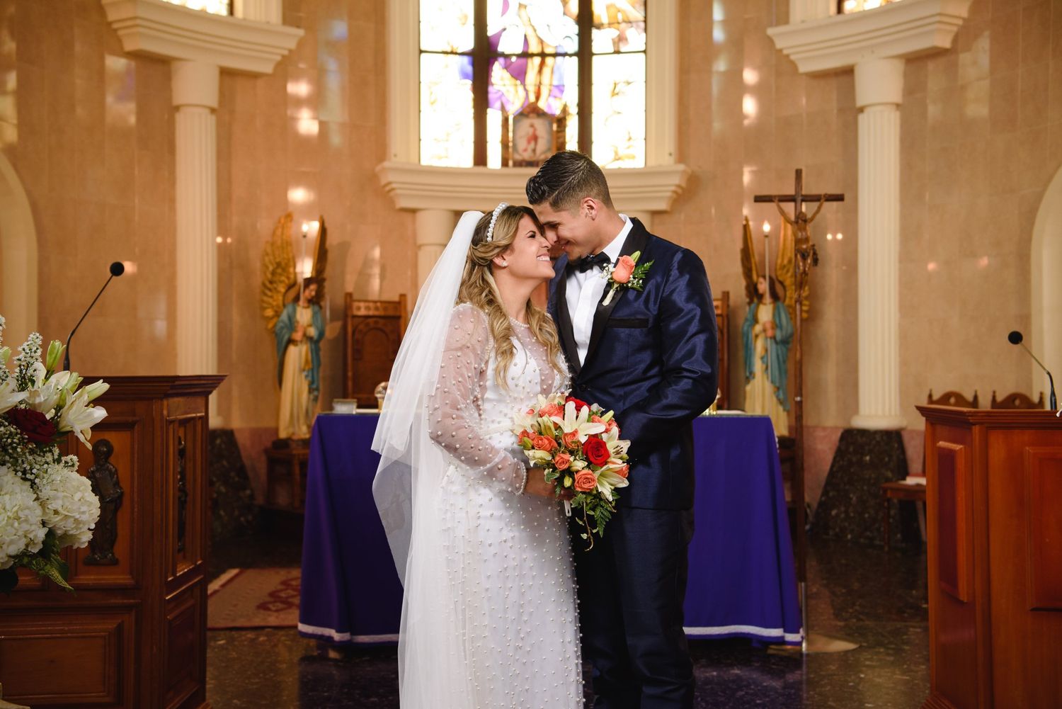 Bride and groom share a romantic kiss at the altar of a beautiful church during their wedding ceremony.