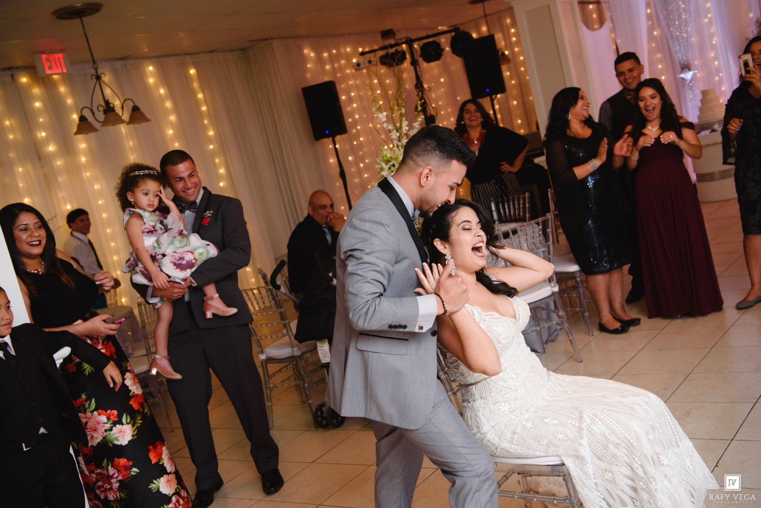 Bride and groom share a joyful dance dip at their elegant wedding reception with guests celebrating in background.