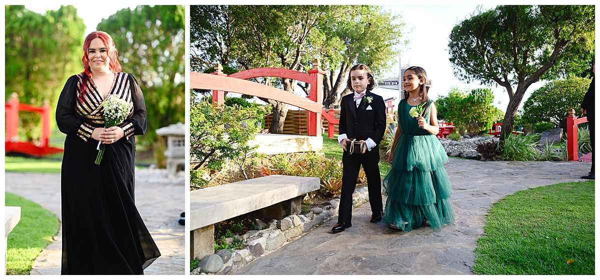 Wedding guests in formal attire posing in a garden venue with lush greenery and red bridge.