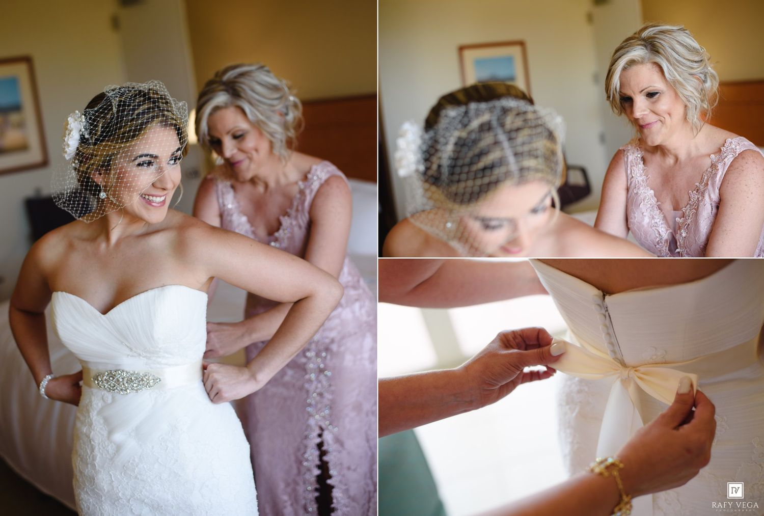 Bride being helped into her wedding dress by a bridesmaid in a pink lace gown, with birdcage veil and crystal belt.