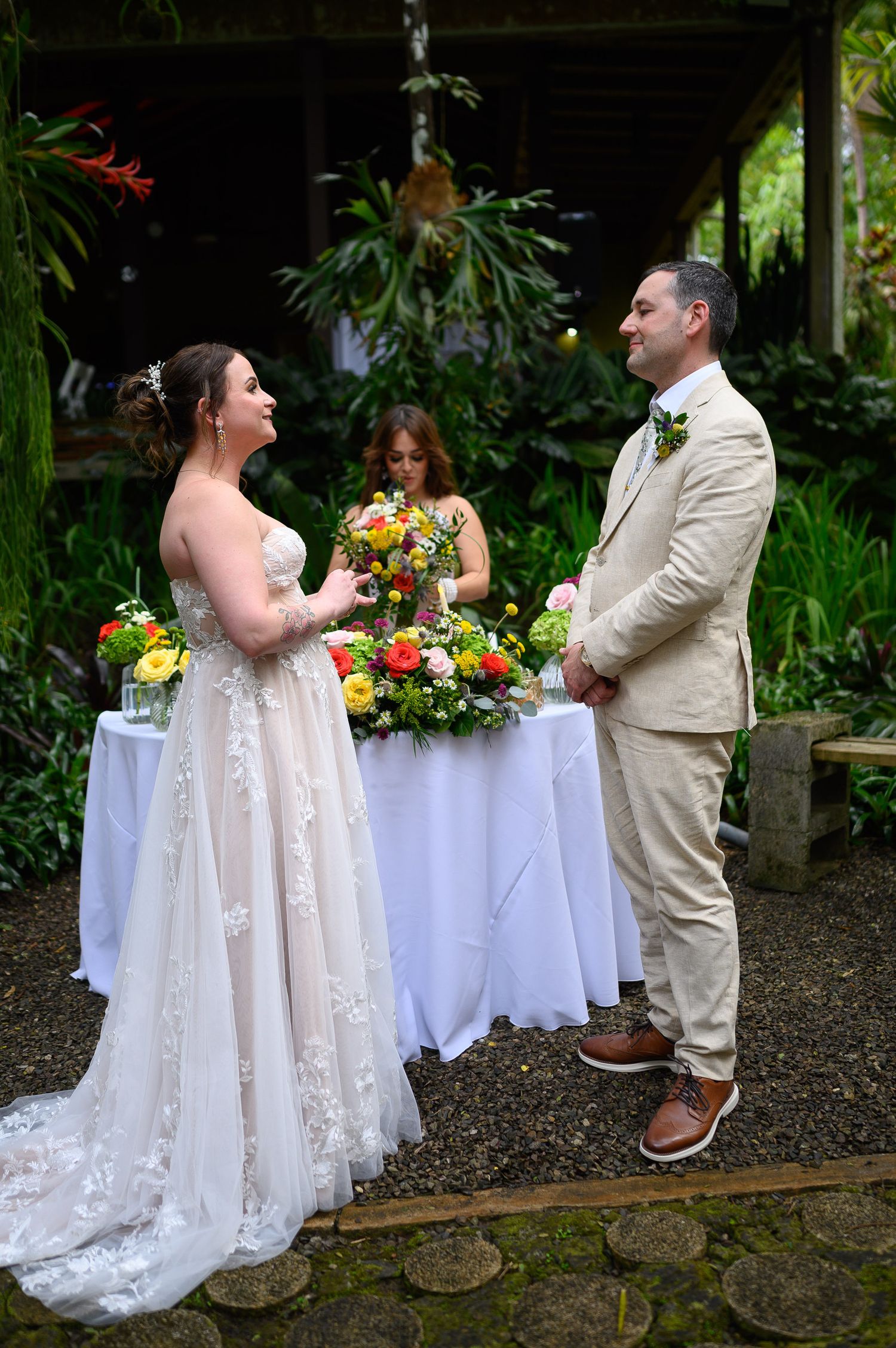 Bride and groom exchange vows outdoors in a lush garden wedding ceremony with colorful floral arrangements.
