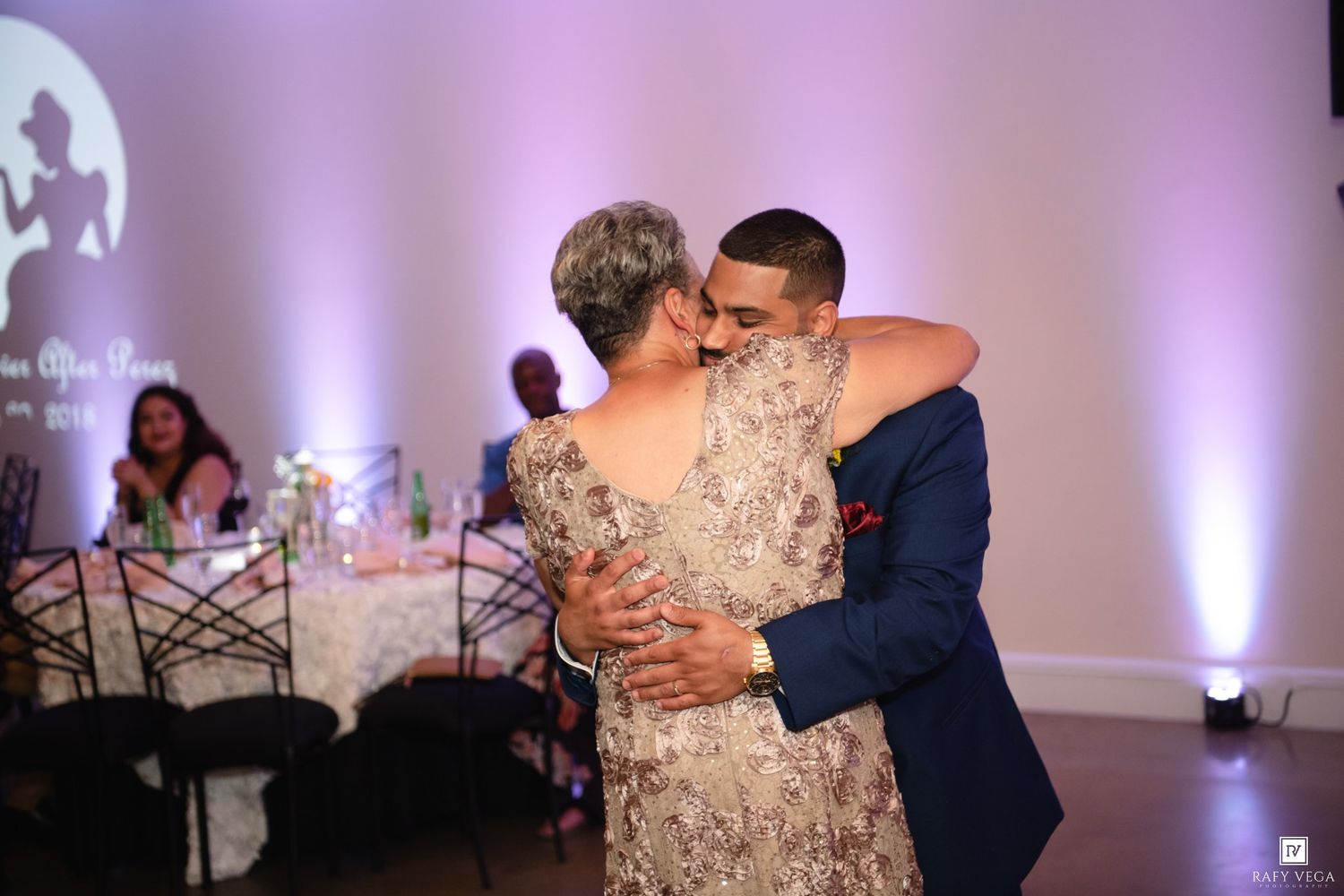 Groom sharing a tender embrace with his mother during the mother-son dance at wedding reception.