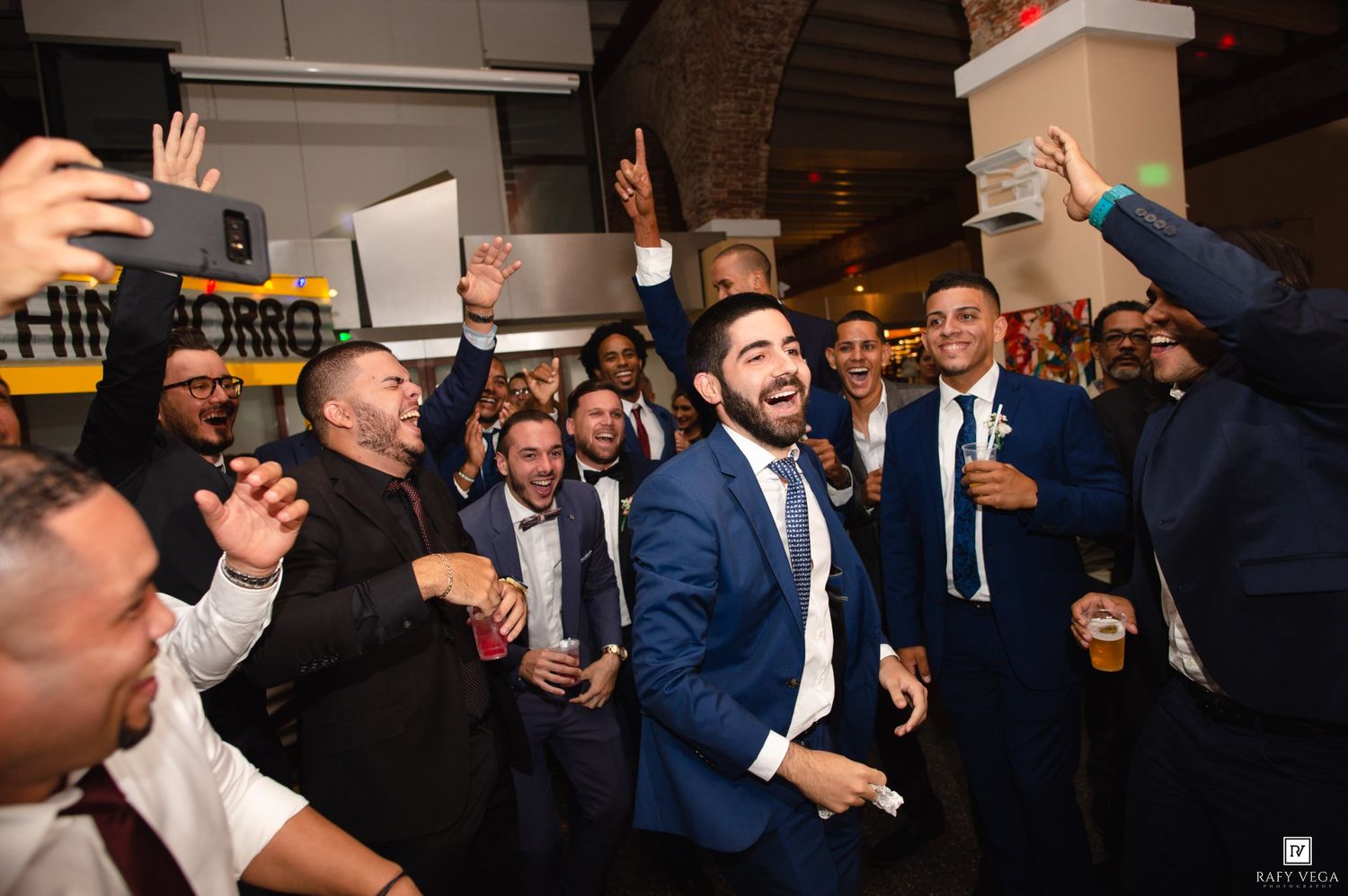 Excited group of men in suits celebrating at a wedding reception party.