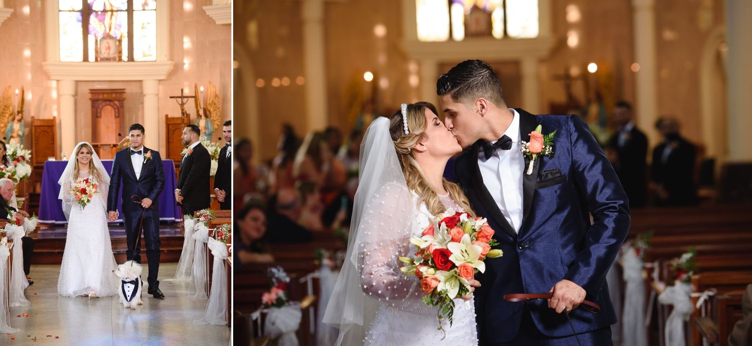 Bride and groom share a kiss at the altar during their church wedding ceremony, surrounded by floral decorations.