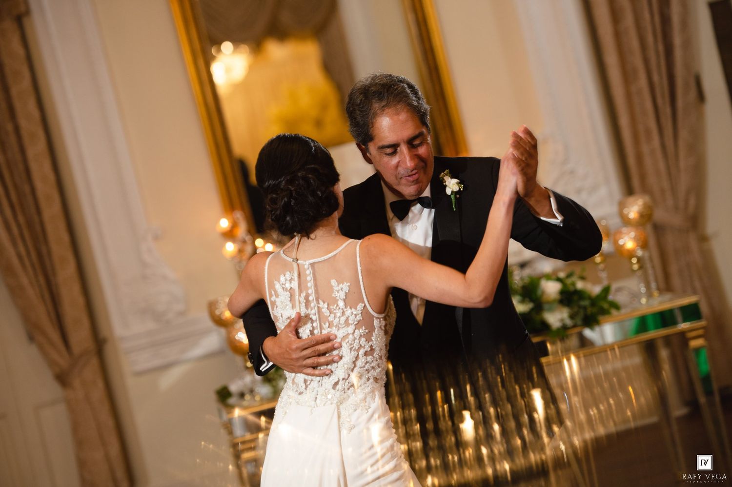 Bride and father share an elegant first dance at a formal wedding reception in a grand ballroom.