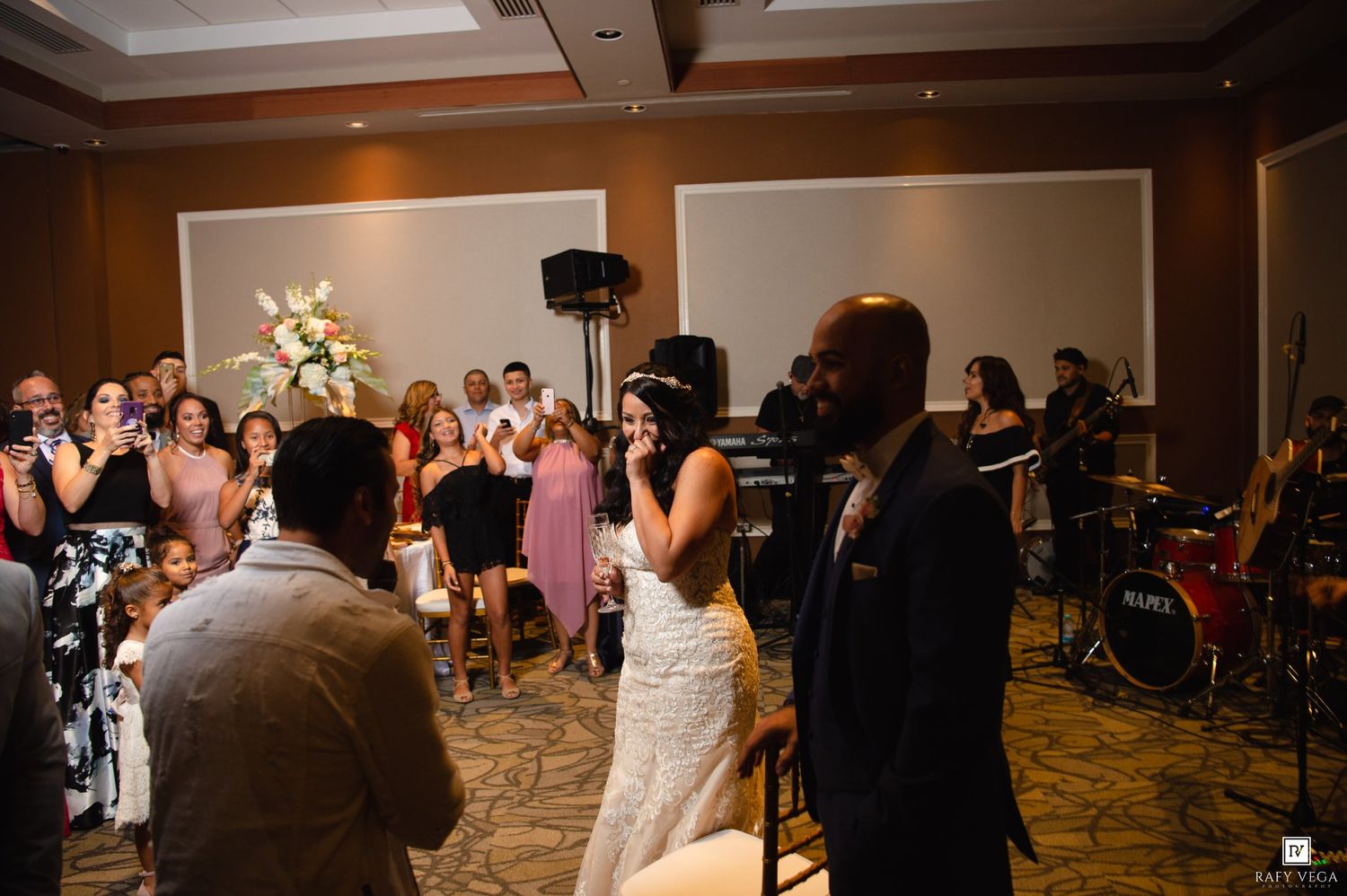 Bride and groom share a joyful moment on the dance floor surrounded by guests at their wedding reception.