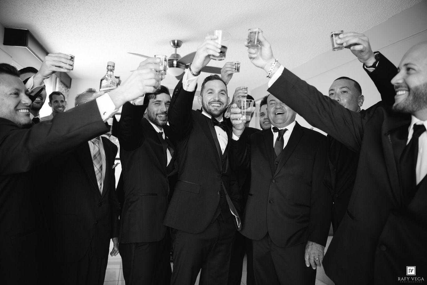 Groom and groomsmen raising glasses in a celebratory toast before the wedding ceremony.